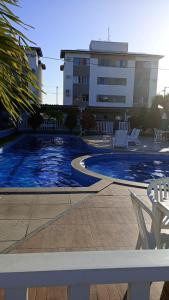 une piscine avec des chaises blanches et un bâtiment dans l'établissement Aconchego da Barra, à Barra dos Coqueiros