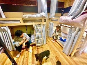 Takibeにある角島シェア&ゲストハウスSumikkoオーシャンビューの犬がいるゲストハウスで特別な交流体験個室とドミトリーの二段ベッドに座る子供のグループが犬と一緒に宿泊します。