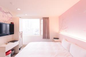 a white bedroom with a bed and a tv at Kiwi Express Hotel - Zhong Zheng Branch in Taichung