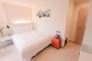 małą sypialnię z łóżkiem i walizką w obiekcie Kiwi Express Hotel - Zhong Zheng Branch w mieście Taizhong