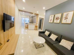- un salon avec un canapé, une télévision et une table dans l'établissement Mường Thanh Oceanus Apartment, à Nha Trang