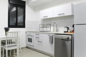 a kitchen with white cabinets and a chair in it at Luxury Family Apartment #26 By Hashdera Eilat in Eilat