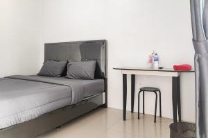 um quarto com uma cama e uma mesa com um banco em RedDoorz Syariah near Lapangan Persijam Jambi em Palmerah