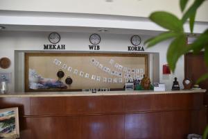 a reception desk with a mirror and clocks on the wall at Hotel Bumi Kitri in Bandung