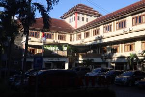 a building with cars parked in a parking lot at Hotel Bumi Kitri in Bandung