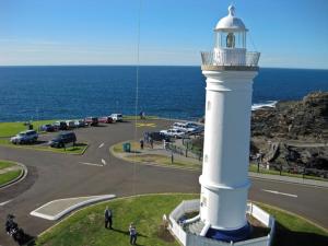 a lighthouse next to a parking lot next to the ocean at Kiama Harbour Cabins in Kiama