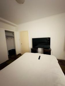 1 dormitorio con 1 cama blanca grande en una habitación en Casa con patio a metros de la playa! en Quequén