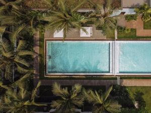 uma vista superior de duas piscinas com palmeiras em Anansaya La Maison em Siem Reap