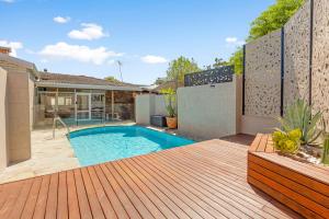 a backyard with a swimming pool and a wooden deck at Maylands Coastal Vibes in Perth