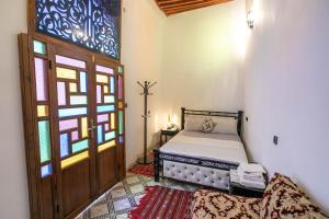 1 dormitorio con cama y vidriera en Riad Fes Allouch, en Fez