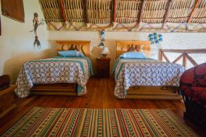 two beds in a room with wooden floors at Casa de Playa Barra Vieja Acapulco in Barra Vieja