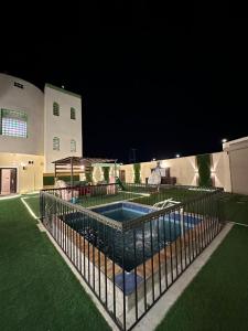 a fence around a swimming pool at night at فيلا الوريك Villa Al Warik in Umm Lujj