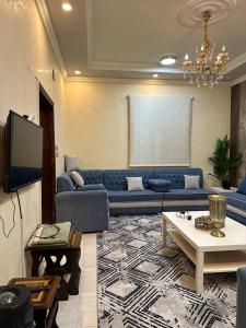 ein Wohnzimmer mit einem blauen Sofa und einem TV in der Unterkunft فيلا الوريك Villa Al Warik in Umm Lajj