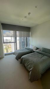 two beds in a bedroom with a large window at Beautiful Ocean View Apartment Signature Broadbeach in Gold Coast