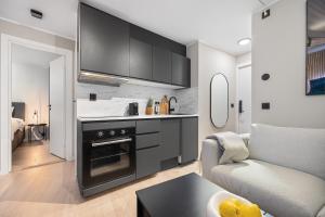 eine Küche mit schwarzen Schränken und ein Wohnzimmer in der Unterkunft King bed - Behind Bryggen - Renovated des 23 in Bergen