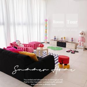 Urban Suites @Jelutong Georgetown في Jelutong: غرفة معيشة مع أريكة سوداء وكراسي وردية