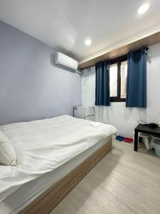 a bedroom with a large white bed with blue curtains at FunSong逢甲 in Taichung