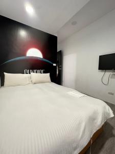 a bedroom with a large white bed with a tv on the wall at FunSong逢甲 in Taichung