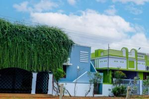 un edificio con un gran árbol verde delante de él en The Peaceful place en Kāraikkudi