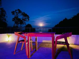 a pink table and two chairs on a balcony at night at Rock n Fall Nature Resort in Ella
