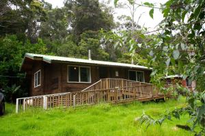 uma cabina de madeira com um deque na relva em The Cabins at Kokee em Waimea