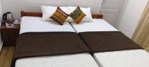 un letto con lenzuola e cuscini marroni e bianchi di Tess Holistay Fort Kochi a Fort Kochi