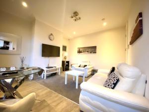 a living room with white furniture and a flat screen tv at Leeds City House in Leeds