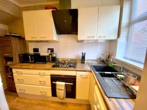 a kitchen with white cabinets and a stove top oven at Leeds City House in Leeds