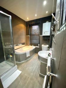 a bathroom with a tub and a toilet and a sink at Leeds City House in Leeds