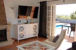 a living room with a fireplace and a tv at Villa Monte Alegrete with sea view in Santa Bárbara de Nexe