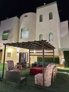 un pabellón con sillas y una mesa frente a un edificio en فيلا الوريك Villa Al Warik, en Umm Lajj