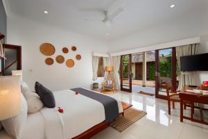 een slaapkamer met een bed en een woonkamer met een bureau bij Utara Villas in Gili Trawangan