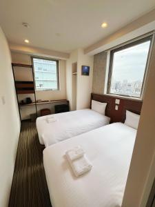 a hotel room with two beds and a window at Nplus HOTEL Tokyo Nihonbashi in Tokyo