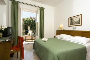 a bedroom with a green bed and a window at Hotel Villa Angelica in Ischia