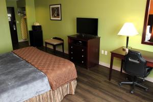 ein Hotelzimmer mit einem Bett und einem Schreibtisch mit einem TV in der Unterkunft Scottish Inns Killeen near Fort Cavazos in Killeen