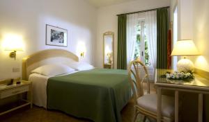 a bedroom with a bed and a table with a chair at Hotel Villa Angelica in Ischia