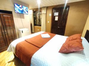 a bedroom with a bed with an orange blanket at Hotel Calle Angosta in Cuenca