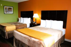 2 Betten in einem Hotelzimmer mit grünen Wänden in der Unterkunft Scottish Inns Killeen near Fort Cavazos in Killeen