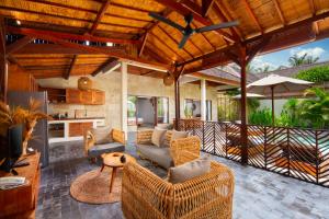 una sala de estar al aire libre con muebles de mimbre y techo de madera. en Utara Villas, en Gili Trawangan