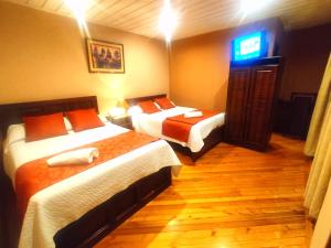 a hotel room with two beds and a television at Hotel Calle Angosta in Cuenca