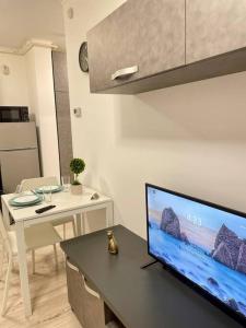 ein Wohnzimmer mit einem TV und einem Tisch mit einem Esszimmer in der Unterkunft Sunlit Shelter * Ideal Location! Free Parking in Oradea