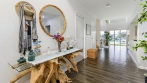 a living room with a console table and a mirror at Luxury & Style On The Canal in Banksia Beach