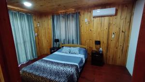 a bedroom with a bed and wood paneled walls at Alojamiento Matheo in El Soberbio