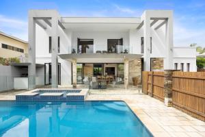 a villa with a swimming pool in front of a house at 6 Witta Circle, Noosa Heads in Noosa Heads