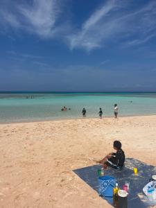 a young child sitting on the beach with a picnic at やどバンブー in Hateruma