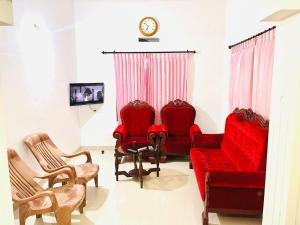 ein Wohnzimmer mit roten Möbeln und einer Uhr in der Unterkunft Manasam Homes in Kunnamangalam