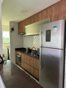a kitchen with a stainless steel refrigerator and wooden cabinets at LINDO AP no Condomínio Topázio in Rio Branco