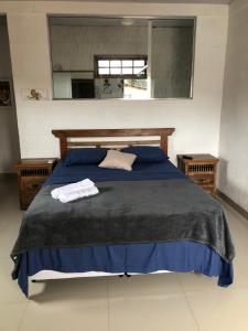 a bedroom with a blue bed with two towels on it at Pousada Chácara da Índia in Itatiaia