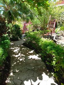 a walkway in a garden with trees and stairs at Pension LE PASSAGE vue jardin in Vaitoare