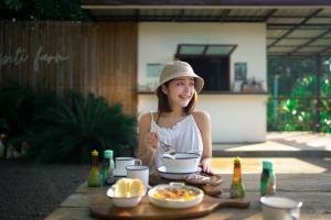kobieta siedząca przy stole z miską jedzenia w obiekcie ปิติฟาร์มมิลี่ คาเฟ่&แกลมปิ้ง ผามออีแดง w mieście Ban Phumsaron